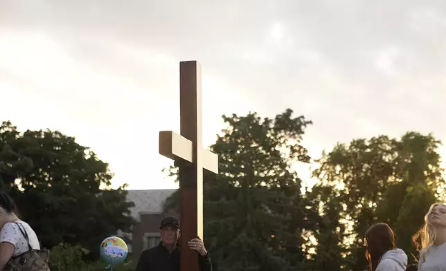 Dan beazley carries a cross at a memorial at Annunciation Catholic Church after Wednesday's school shooting, Thursday, Aug. 28, 2025, in Minneapolis. (AP Photo/Abbie Parr)