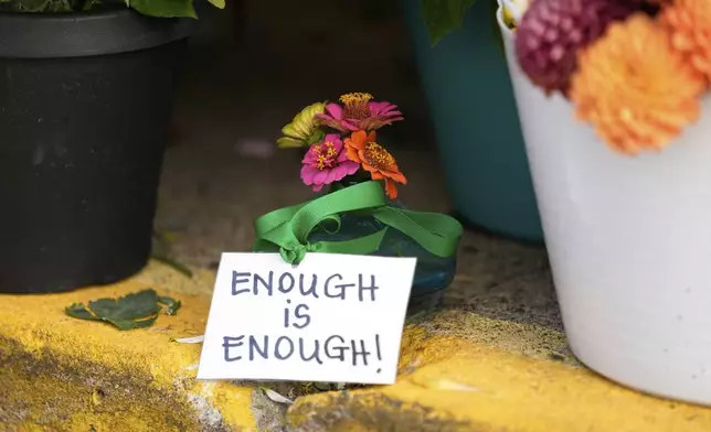 A sign stands amid flowers at a memorial at Annunciation Catholic Church after Wednesday's school shooting, Thursday, Aug. 28, 2025, in Minneapolis. (AP Photo/Abbie Parr)