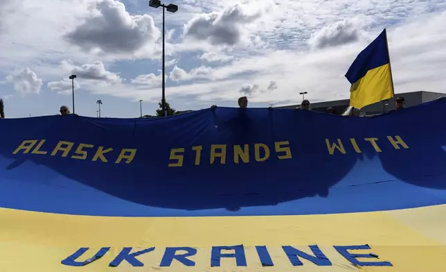 People hold a large Ukrainian flag during a rally in Anchorage, Alaska, Thursday, Aug. 14, 2025, ahead of a meeting between President Donald Trump and Russia's President Vladimir Putin. (AP Photo/Jae C. Hong)
