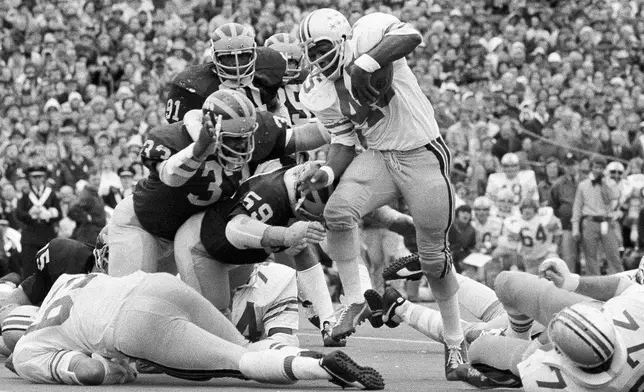 FILE - Ohio State's Archie Griffin picks up some of his game-high 163 yards against Michigan during an NCAA college football game in Ann Arbor, Mich., as Michigan's Walt Williamson (91), Carl Russ (33) and Steve Strinko (59) defend. (AP Photo/File)