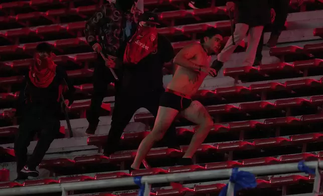 Fans of Argentina's Independiente attack a Universidad de Chile fan, right, after they stripped him of his clothing during a Copa Sudamericana round of sixteen second leg soccer match at the Libertadores de America stadium in Avellaneda, Argentina, Wednesday, Aug. 20, 2025. (AP Photo/Gustavo Garello)
