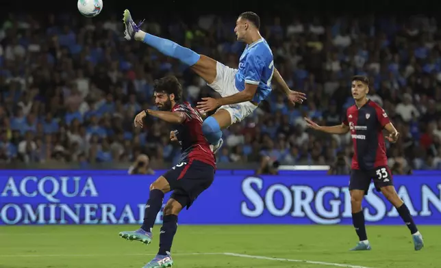 Napoli's Lorenzo Lucca kick a high ball over Cagliari's Sebastiano Luperto during the Serie A soccer match between Napoli and Cagliari at the Diego Armando Maradona Stadium in Naples, Italy, Saturday, Aug. 30 , 2025. (Alessandro Garofalo/LaPresse via AP)