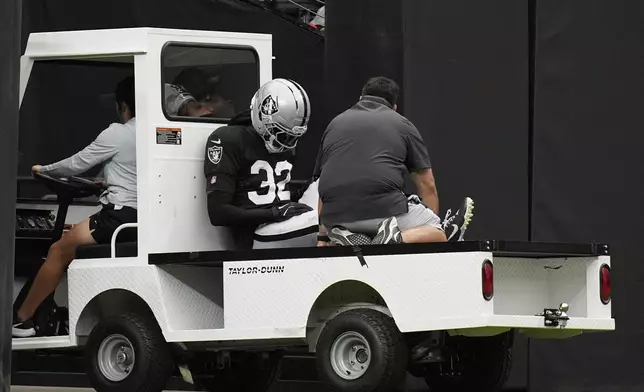Las Vegas Raiders cornerback Lonnie Johnson Jr. (32) is carted off the field at the team's NFL football training camp Saturday, Aug. 2, 2025, in Las Vegas. (AP Photo/John Locher)