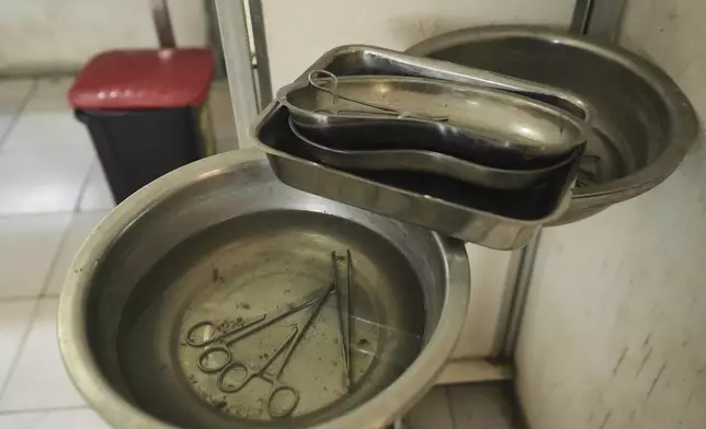 Surgical scissors and scalpels lye in fly-infested water at a government hospital in Konduga, in northeast Nigeria's Borno state, Wednesday, July 23, 2025. (AP Photo/Sunday Alamba)