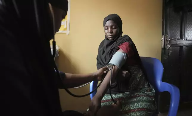 A midwife checks a Falmata Muhammed's blood pressure at a facility run by aid agency International Rescue Committee, in Magumeri, in northeast Nigeria's Borno state, Tuesday, July 22, 2025. (AP Photo/Sunday Alamba)
