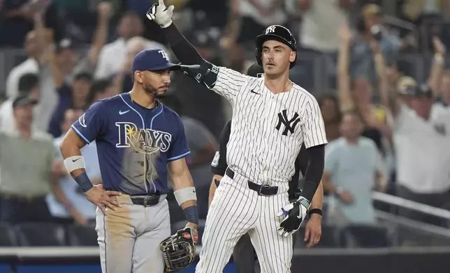 Tampa Bay Rays shortstop José Caballero watches as New York Yankees' Cody Bellinger gestures to teammates after hitting an RBI triple during the 10th inning of a baseball game Wednesday, July 30, 2025, in New York. (AP Photo/Frank Franklin II)