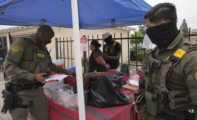 A woman is detained by U.S. Border Patrol agents outside a Home Depot Friday, Aug. 15, 2025, in Los Angeles. (AP Photo/Gregory Bull)
