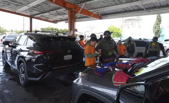 Immigration agents conduct arrests and check identifications at a car wash on Friday, Aug. 15, 2025, in Montebello, Calif. (AP Photo/Gregory Bull)