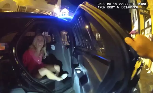 In an image taken from police body camera footage, a Newport Police officer closes the door of a cruiser with the detained Rhode Island Special Assistant Attorney General Devon Flanagan after an encounter that ended with officers detaining Flanagan on trespassing charges, Aug. 14, 2025, in Newport, R.I. (Newport Police Department via AP)