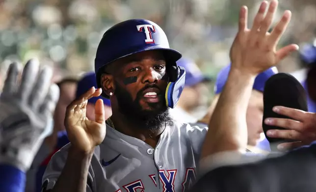 Texas Rangers' Adolis García celebrates in the dugout after scoring during the ninth inning of a baseball game against the Athletics Saturday, Aug. 30, 2025, in West Sacramento, Calif. (AP Photo/Sara Nevis)