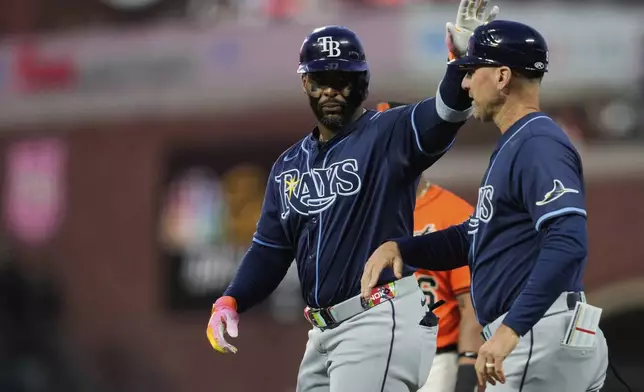Tampa Bay Rays' Yandy Díaz, left, celebrates with first base coach Michael Johns, right, after hitting an RBI single during the third inning of a baseball game against the San Francisco Giants, Friday, Aug. 15, 2025, in San Francisco. (AP Photo/Godofredo A. Vásquez)