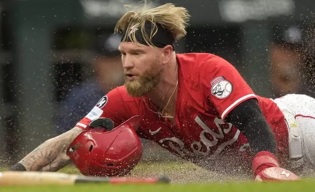 Cincinnati Reds' Jake Fraley dives safely into home plate to score on a double hit by Tyler Stephenson during the second inning of a baseball game against the Atlanta Braves, Thursday, July 31, 2025, in Cincinnati. (AP Photo/Carolyn Kaster)