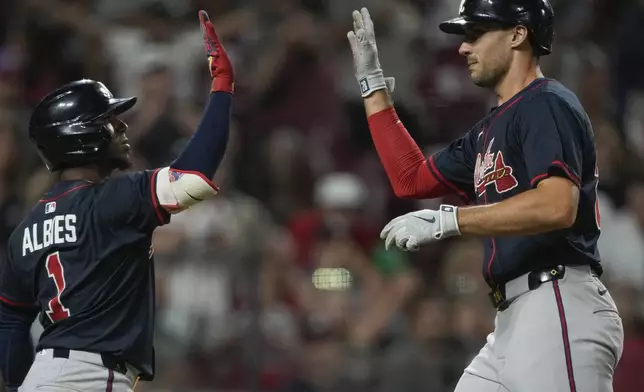 Atlanta Braves' Matt Olson, right, celebrates with Ozzie Albies after scoring on a sacrifice fly hit by Marcell Ozuna during the tenth inning of a baseball game against the Cincinnati Reds, Thursday, July 31, 2025, in Cincinnati. (AP Photo/Carolyn Kaster)