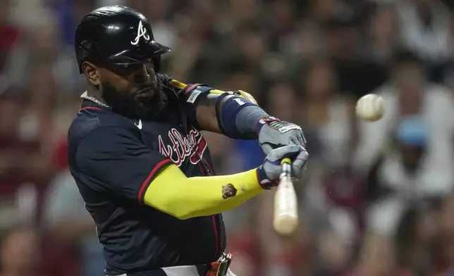 Atlanta Braves designated hitter Marcell Ozuna hits a sacrifice fly to score Matt Olson during the tenth inning of a baseball game against the Cincinnati Reds, Thursday, July 31, 2025, in Cincinnati. (AP Photo/Carolyn Kaster)