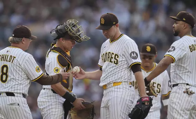 San Diego Padres starting pitcher Michael King, center, hands the ball to manager Mike Shildt (8) as he exits during the third inning of a baseball game against the Boston Red Sox Saturday, Aug. 9, 2025, in San Diego. (AP Photo/Gregory Bull)