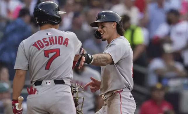 Boston Red Sox's Jarren Duran, right, celebrates with teammate Masataka Yoshida (7) after scoring from third base on a balk during the third inning of a baseball game against the San Diego Padres Saturday, Aug. 9, 2025, in San Diego. (AP Photo/Gregory Bull)