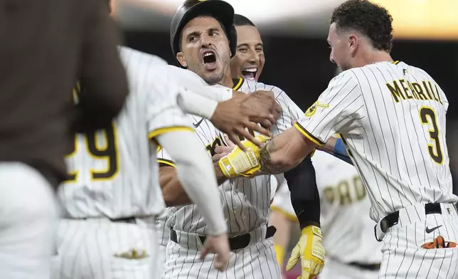San Diego Padres' Ramon Laureano, center, is swarmed by teammates after hitting a walk-off RBI single during the tenth inning of a baseball game Saturday, Aug. 9, 2025, in San Diego. The Padres won 5-4. (AP Photo/Gregory Bull)