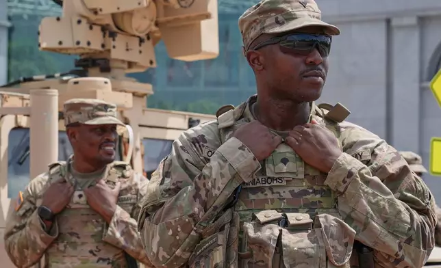 District of Columbia National Guard soldiers keep watch as travelers arrive at the entrance to Union Station near the Capitol, Thursday, Aug 14, 2025, in Washington. (AP Photo/Mariam Zuhaib)
