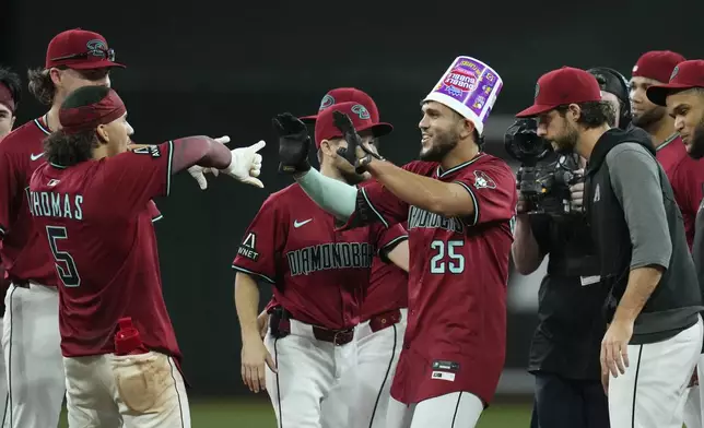 Arizona Diamondbacks' Adrian Del Castillo (25) celebrates his walk-off single against the Cleveland Guardians with teammates, including Alek Thomas (5) and Zac Gallen, right, after a baseball game Wednesday, Aug. 20, 2025, in Phoenix. (AP Photo/Ross D. Franklin)