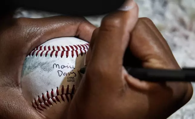 Mo'ne Davis autographs baseballs during the fourth day of tryouts for the Women's Professional Baseball League, Monday, Aug. 25, 2025, at Nationals Park in Washington. (AP Photo/Julia Demaree Nikhinson)