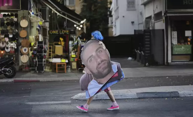 A demonstrator carries a photo of Israeli hostage Segev Kalfon who is held in the Gaza Strip, during a protest demanding the release of all hostages from Hamas captivity and calling for an end to the war, in Tel Aviv, Israel, Thursday, Aug. 7, 2025. (AP Photo/Ariel Schalit)