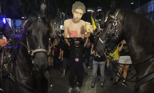 A demonstrator holds a photo of Israeli hostage Evyatar David, who is being held in the Gaza Strip, during a protest demanding the release of all hostages from Hamas captivity and an end to the war, in Tel Aviv, Israel, Thursday, Aug. 7, 2025. (AP Photo/Ariel Schalit)