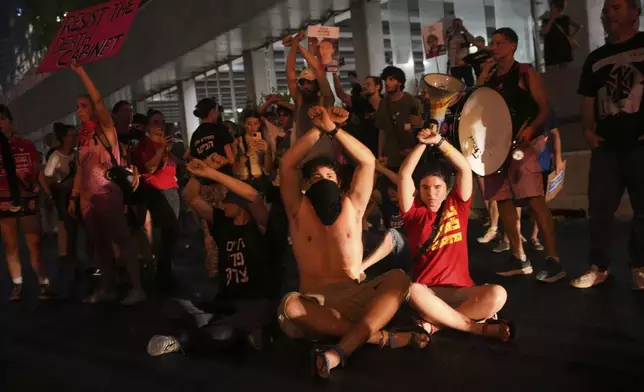 Demonstrators block a highway during a protest demanding the release of all hostages held by Hamas in the Gaza Strip and calling for an end to the war, in Tel Aviv, Israel, Saturday, Aug. 9, 2025. (AP Photo/Ohad Zwigenberg)
