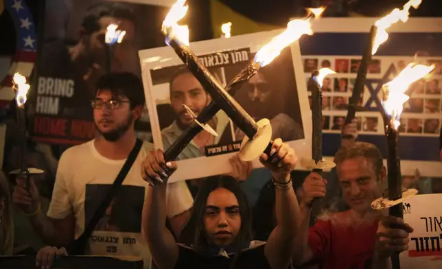 Demonstrators light torches during a protest demanding the immediate release of all hostages from Hamas captivity in the Gaza Strip and calling for an end to the war, outside the prime minister's office in Jerusalem, Thursday, Aug. 7, 2025. (AP Photo/Ohad Zwigenberg)