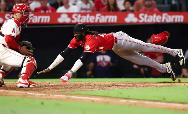 Cincinnati Reds' Elly De La Cruz, right, slides into home plate to score as Los Angeles Angels catcher Logan O'Hoppe, left, watches during the fifth inning of a baseball game, Monday, Aug. 18, 2025, in Anaheim, Calif. (AP Photo/Jessie Alcheh)