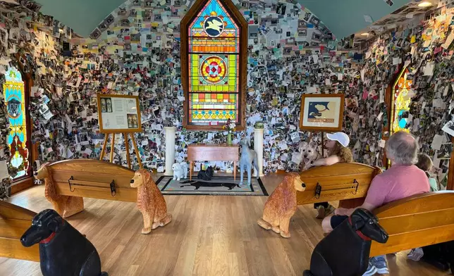 Visitors sit in the Dog Chapel at Dog Mountain, a 150-acre dog park created by Vermont folk artist Stephen Huneck, Thursday, Aug. 7, 2025, in St. Johnsbury, Vt. (AP Photo/Amanda Swinhart)