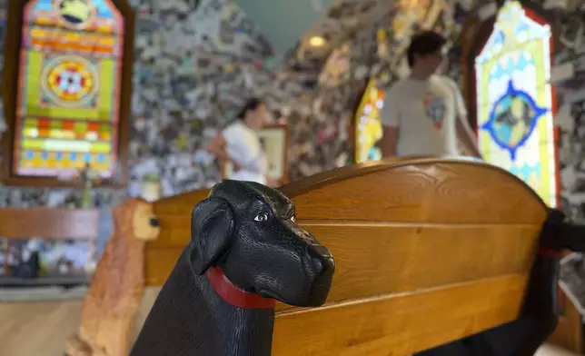 A black lab carved into a wooden pew is pictured in the Dog Chapel at Dog Mountain, a 150-acre dog park created by Vermont folk artist Stephen Huneck, Thursday, Aug. 7, 2025, in St. Johnsbury, Vt. (AP Photo/Amanda Swinhart)