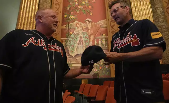 Former Atlanta Braves infielder Nick Green, right, signs an autograph for Darryl Runde, left, during a watch party, Friday, Aug. 1, 2025, in Bristol, Tenn., the day before the MLB Speedway Classic baseball game between the Cincinnati Reds and Atlanta Braves. (AP Photo/George Walker IV)