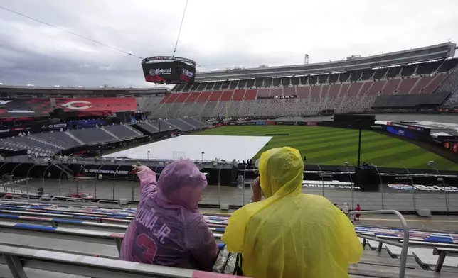 Fans wait in the rain before the MLB Speedway Classic baseball game between the Cincinnati Reds and the Atlanta Braves at Bristol Motor Speedway in Bristol, Tenn., Saturday, Aug. 2, 2025. (AP Photo/George Walker IV)