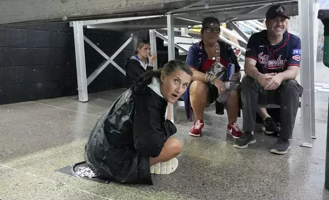 Fans wait out a rain delay at the MLB Speedway Classic baseball game between the Atlanta Braves and the Cincinnati Reds at Bristol Motor Speedway in Bristol, Tenn., Saturday, Aug. 2, 2025. (AP Photo/George Walker IV)