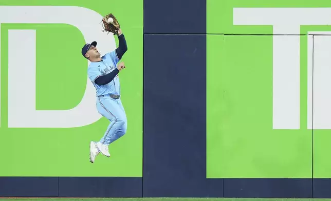 Toronto Blue Jays outfielder Daulton Varsho (5) makes a leaping catch against the Chicago Cubs during the fifth inning of a baseball game in Toronto on Wednesday, Aug. 13, 2025. (Nathan Denette/The Canadian Press via AP)