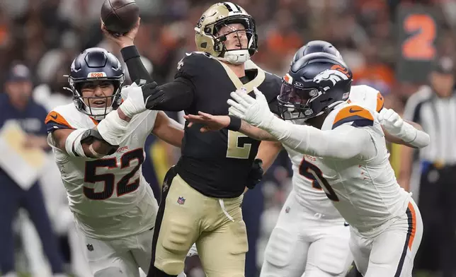 New Orleans Saints quarterback Spencer Rattler, center, is hit by Denver Broncos linebackers Jonah Elliss, left, Justin Strnad, back right, and Jonathon Cooper in the first half of an NFL preseason football game Saturday, Aug. 23, 2025, in New Orleans. (AP Photo/Gerlad Herbert)