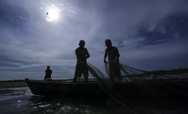 FILE - Men look for fish in the Amazon River amid a drought on the outskirts of Leticia, Colombia, Monday, Oct. 21, 2024. (AP Photo/Ivan Valencia, File)