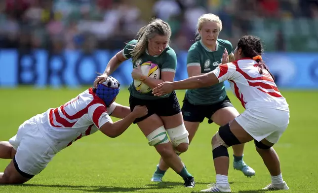 Ireland's Edel McMahon, center, is tackled by Japan's Sachiko Kato, left and Japan's Seina Saito during the group C match between Ireland and Japan of the 2025 Women's Rugby World Cup, in Northampton, England, Sunday, Aug. 24, 2025. (Joe Giddens/PA via AP)