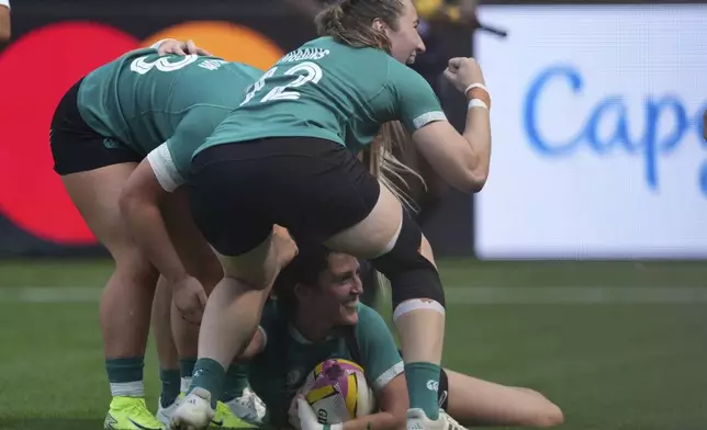 Players celebrate as Ireland's Amee Leigh Costigan, down, scored a try during the group C match at the 2025 Women¥s Rugby World Cup between Ireland and Japan in Northampton, England, Sunday, Aug. 24, 2025. (AP Photo/Dave Shopland)