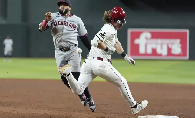 Arizona Diamondbacks' Jake McCarthy, right, runs out an infield single as Cleveland Guardians first baseman Carlos Santana, left, is unable to make a catch on a throwing error allowing Diamondbacks' McCarthy to advance to second base during the sixth inning of a baseball game Tuesday, Aug. 19, 2025, in Phoenix. (AP Photo/Ross D. Franklin)