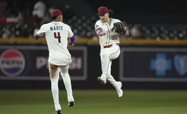 Arizona Diamondbacks' Ketel Marte (4) and Alek Thomas, right, celebrate a win against the Cleveland Guardians after a baseball game Tuesday, Aug. 19, 2025, in Phoenix. (AP Photo/Ross D. Franklin)