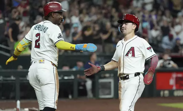 Arizona Diamondbacks' Geraldo Perdomo (2) and Corbin Carroll celebrate their runs scored against the Cleveland Guardians during the seventh inning of a baseball game Tuesday, Aug. 19, 2025, in Phoenix. (AP Photo/Ross D. Franklin)