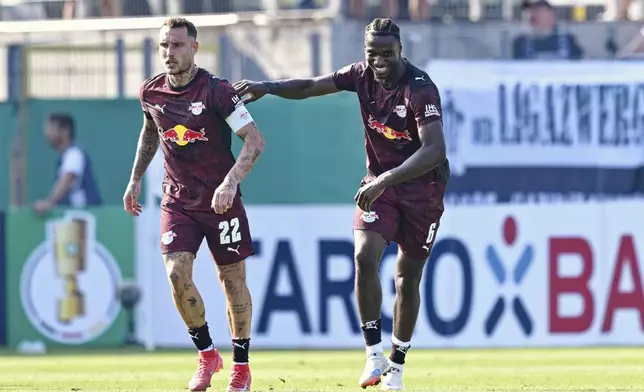 Leipzig's Ezechiel Banzuzi, right, celebrates after scoring his side's third goal during the German soccer cup first round match between SV Sandhausen and RB Leipzig in Sandhausen, Germany, Saturday, Aug. 16, 2025. (Uwe Anspach/dpa via AP)