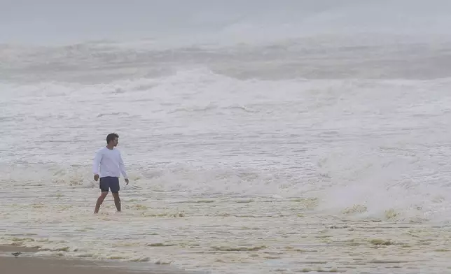 A person watches as waves from Hurricane Erin crash along beach in Duck, N.C., on Thursday, Aug. 21, 2025. (AP Photo/Pablo Martinez Monsivais)