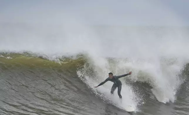 A surfer rides waves bolstered by Hurricane Erin at Rockaway Beach in the Queens borough of New York, Thursday, Aug. 21, 2025. (AP Photo/Seth Wenig)