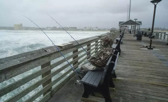 Sebastian Kettner fishes on Jennette's Pier as waves from Hurricane Erin crash ashore in Nags Head, N.C., Thursday, Aug. 21, 2025. (AP Photo/Allen G. Breed)