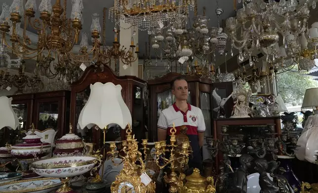 A seller of chandeliers and decorative items stand at his shop during power outage in Tehran, Iran, Tuesday, Aug. 5, 2025. (AP Photo/Vahid Salemi)