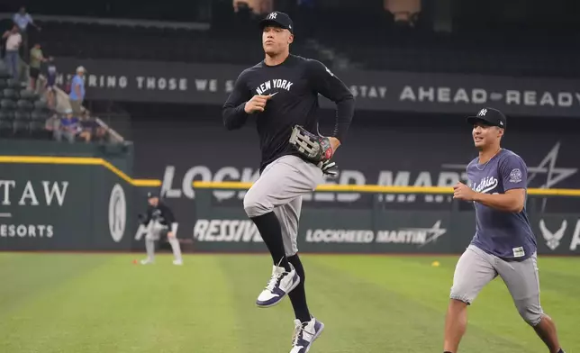 New York Yankees outfielder Aaron Judge, left, warms up before a baseball game against the Texas Rangers, Tuesday, Aug. 5, 2025, in Arlington, Texas. (AP Photo/LM Otero)