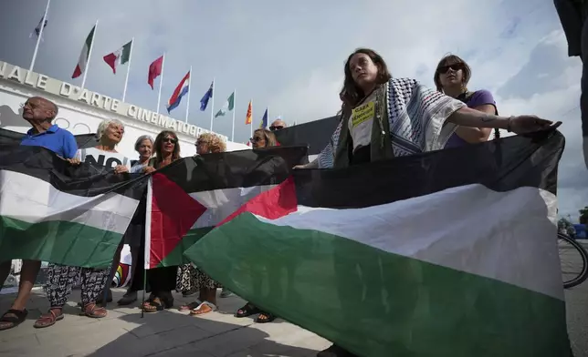 Pro Palestine demonstrators hold Palestinian flags during a press conference in front of the red carpet to announce a demonstration on Saturday, Aug. 30 during the 82nd edition of the Venice Film Festival in Venice, Italy, on Wednesday, Aug. 27, 2025. (Photo by Alessandra Tarantino/Invision/AP)