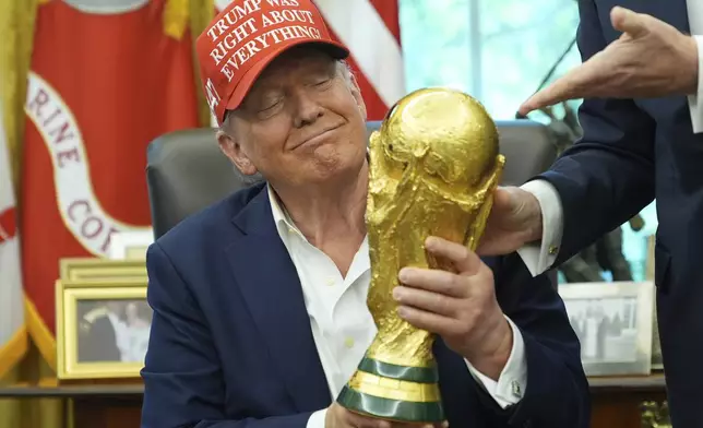President Donald Trump holds the FIFA World Cup Winners Trophy during an announcement in the Oval Office of the White House, Friday, Aug. 22, 2025, in Washington. (AP Photo/Jacquelyn Martin)